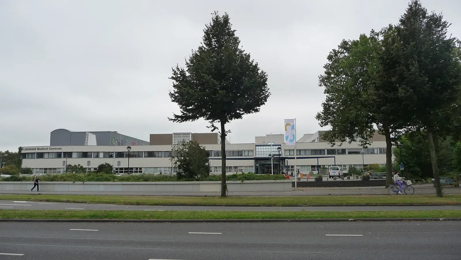 Spijkenisse Medisch Centrum gezien vanaf de overkant van de weg, laag ziekenhuisgebouw achter bomen