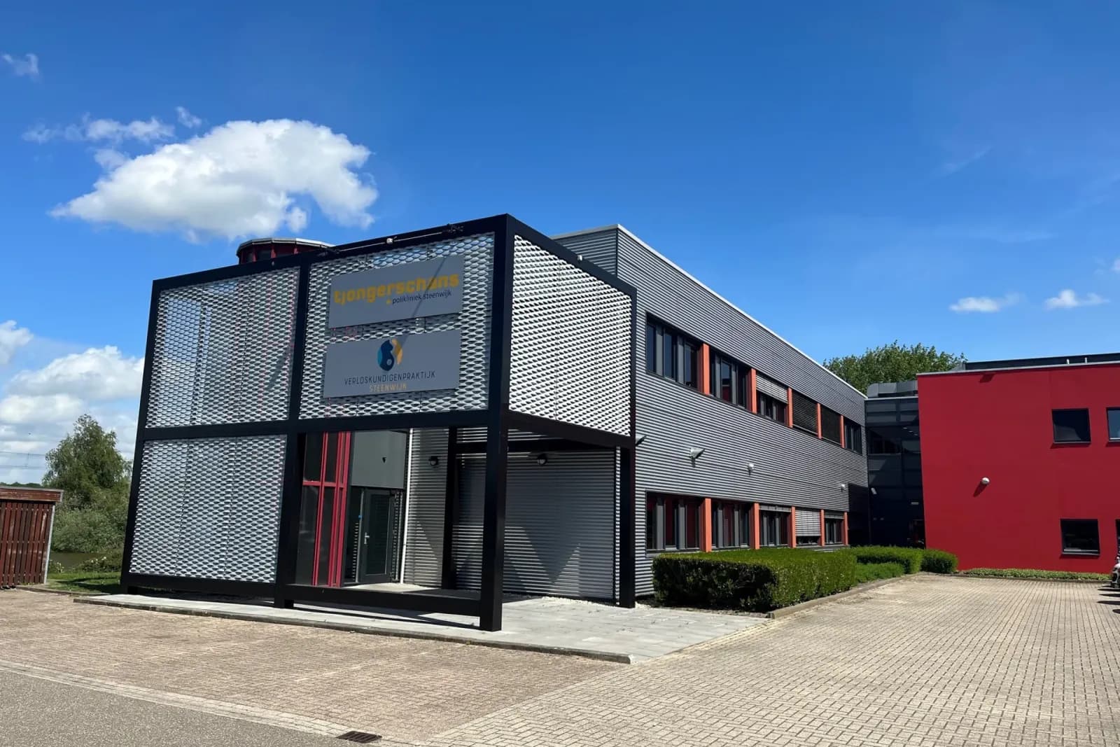 Gebouw van de polikliniek Steenwijk met donkere metalen entreepartij; op de foto staat nog het oude bord van Tjongerschans