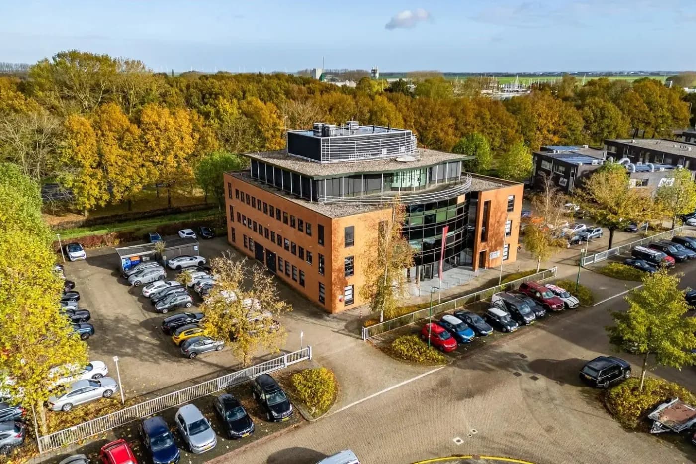 Luchtfoto van het gebouw aan de Baarnsche Dijk in Baarn met parkeerterrein, de nieuwe locatie van Meander