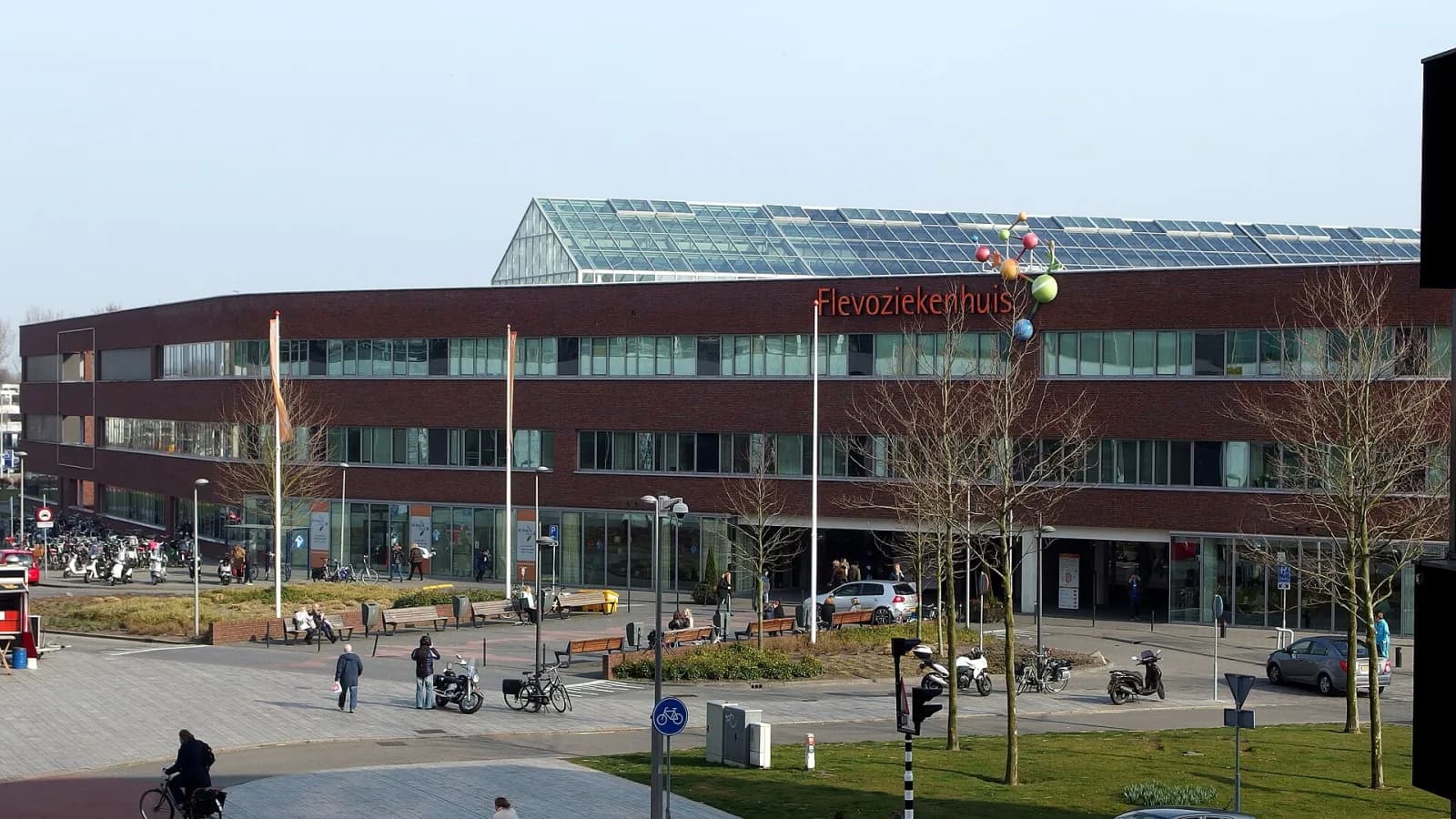 Voorkant van het Flevoziekenhuis in Almere met de naam op de bakstenen gevel, het glazen dak en het voorplein