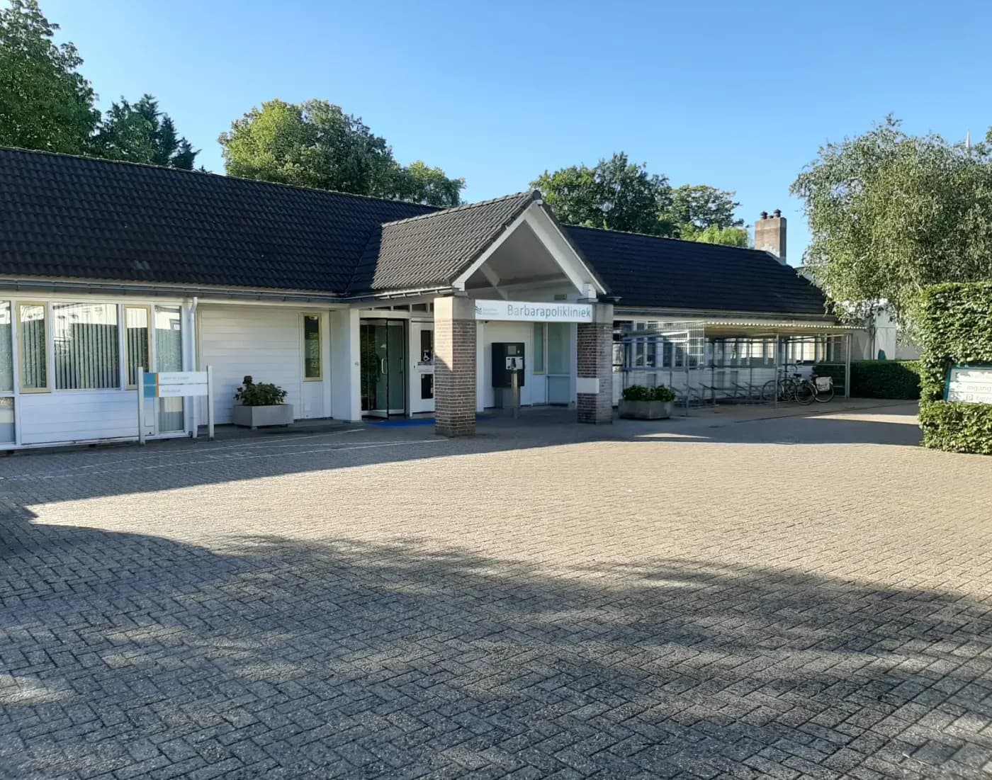 Het laagbouwgebouw van de Barbarapolikliniek in Culemborg met de ingang en het voorplein