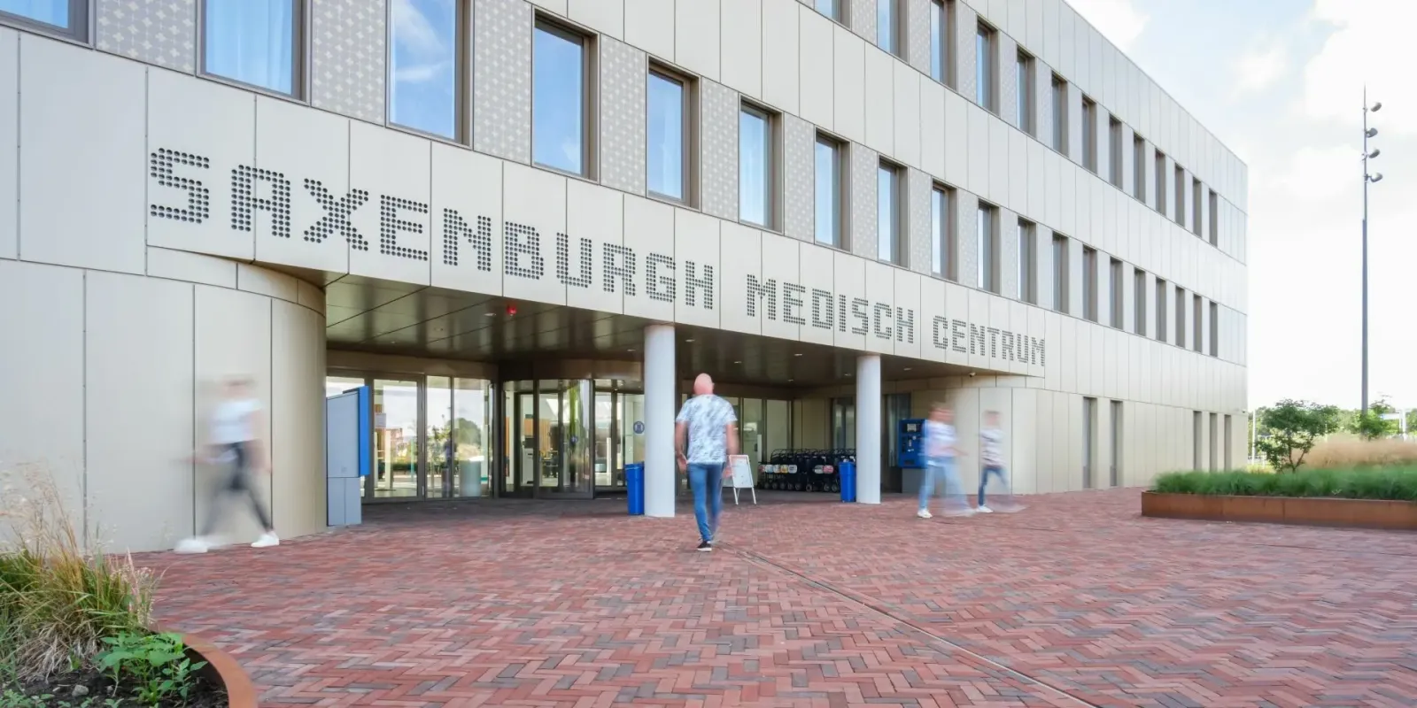 Gevel van Saxenburgh Medisch Centrum met de naam op het gebouw en het plein voor de hoofdingang