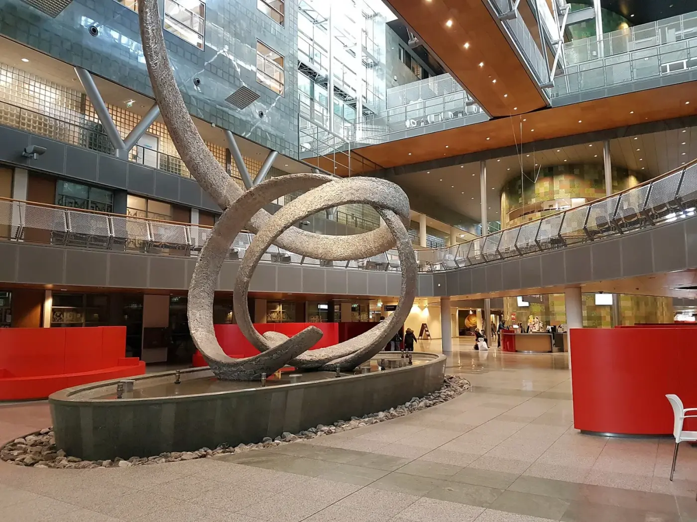Atrium van Zuyderland Sittard-Geleen met een groot kunstwerk van gebogen ringen boven een waterpartij
