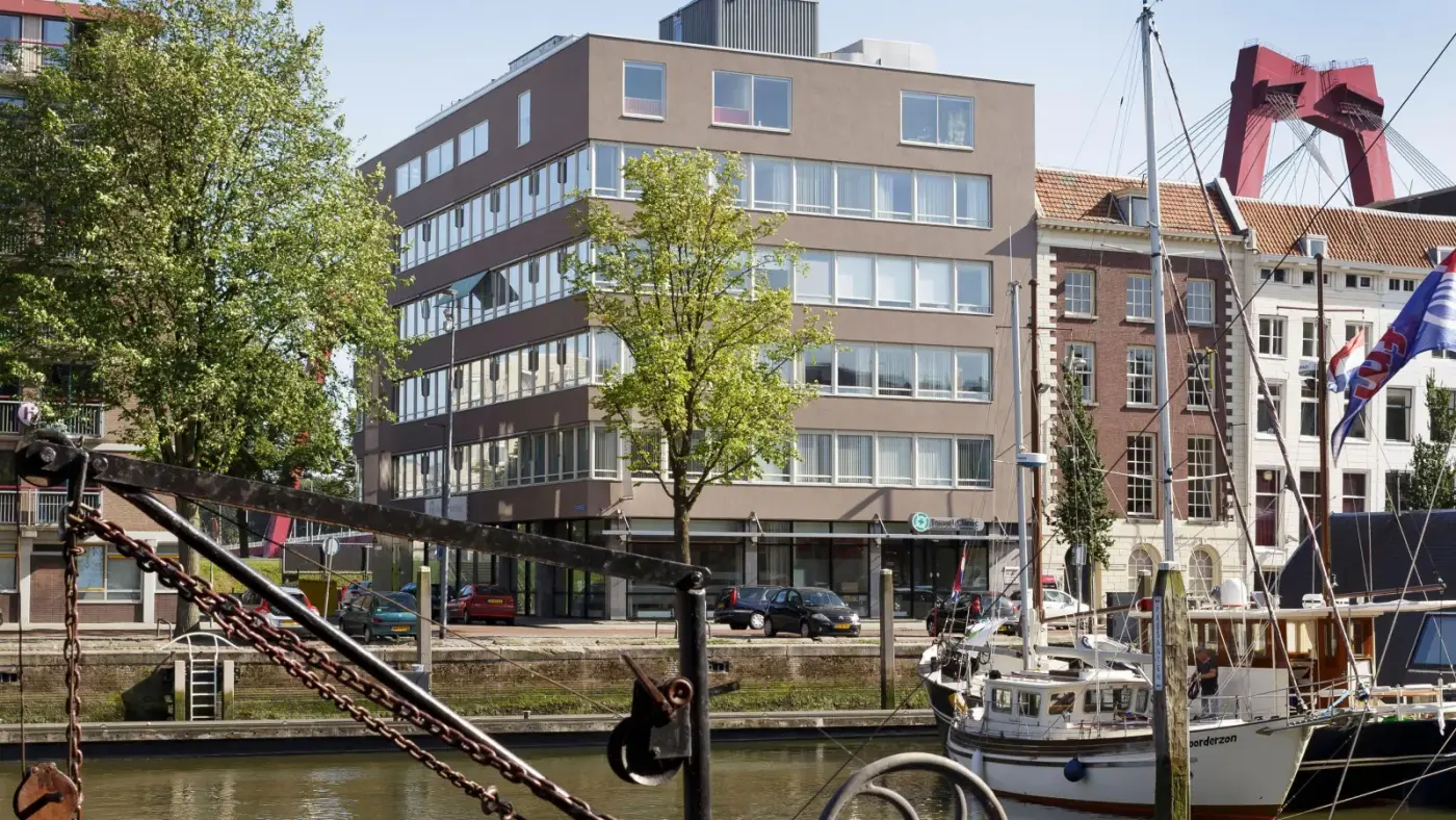 Het kantoorgebouw Haringvliet 72 aan de Oude Haven in Rotterdam, gezien vanaf het water, met de Willemsbrug op de achtergrond
