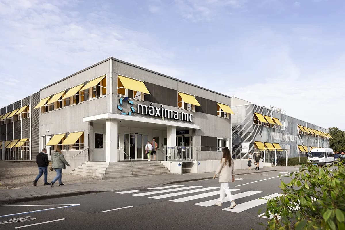 Gebouw van Máxima MC in Veldhoven met het logo boven de ingang en gele zonneschermen
